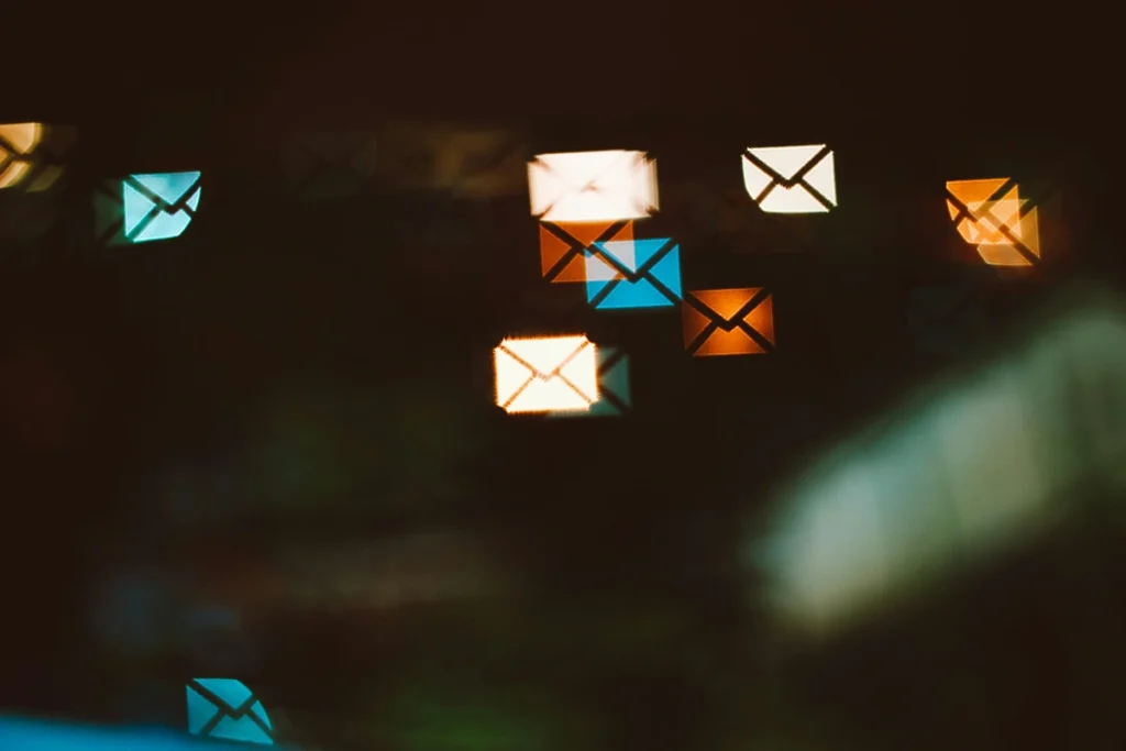 Abstract image of black screen with a mail logo of an envelope floating on the screen in multiple colors