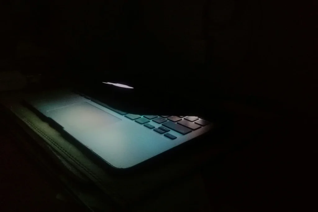 Image of an Apple laptop mostly closed in a dark environment