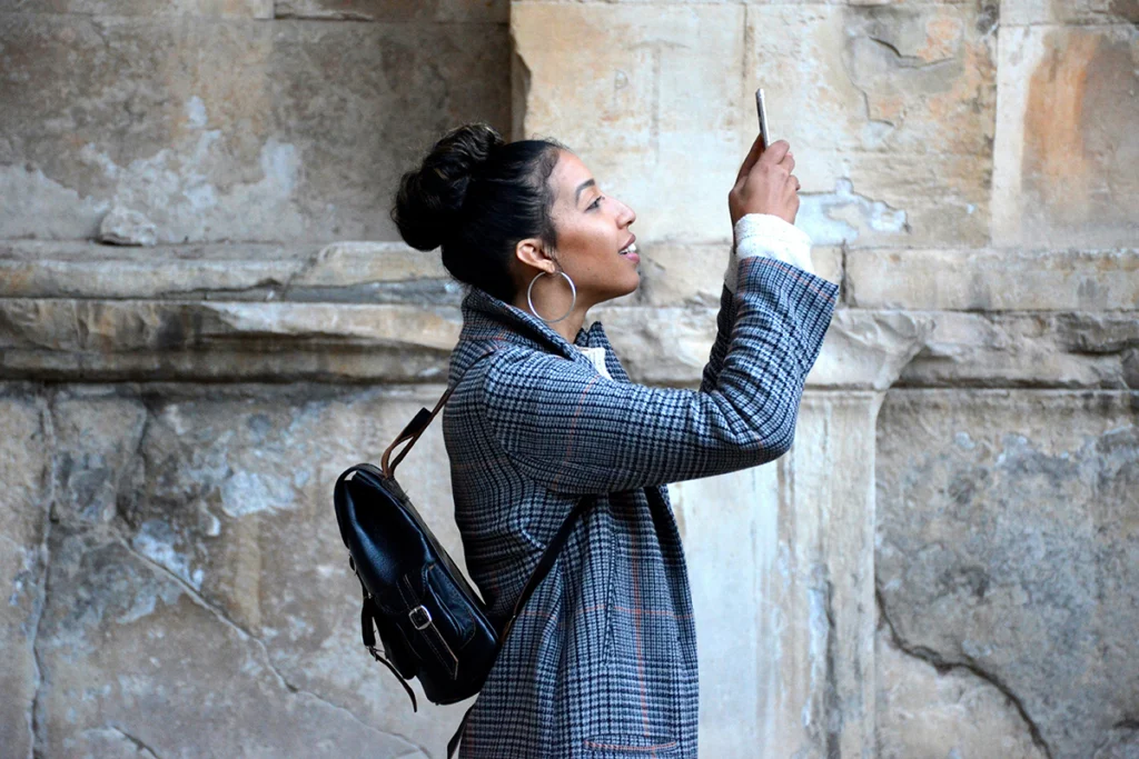 Image of person in front of stone wall taking an image with their cell phone