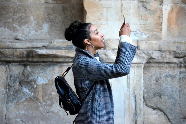 Image of person in front of stone wall taking an image with their cell phone