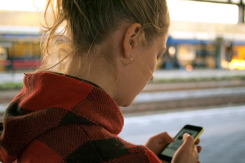Image of a person's head from the back outside looking at a cell phone