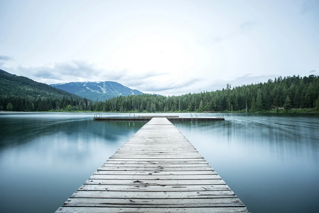 Image of a dock on a lake with mountains and trees in the background