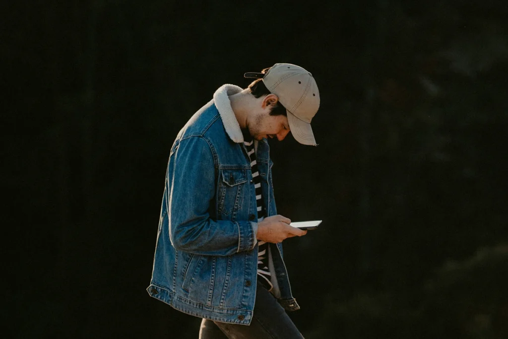 Image of a person walking outside head down on their cellphone.