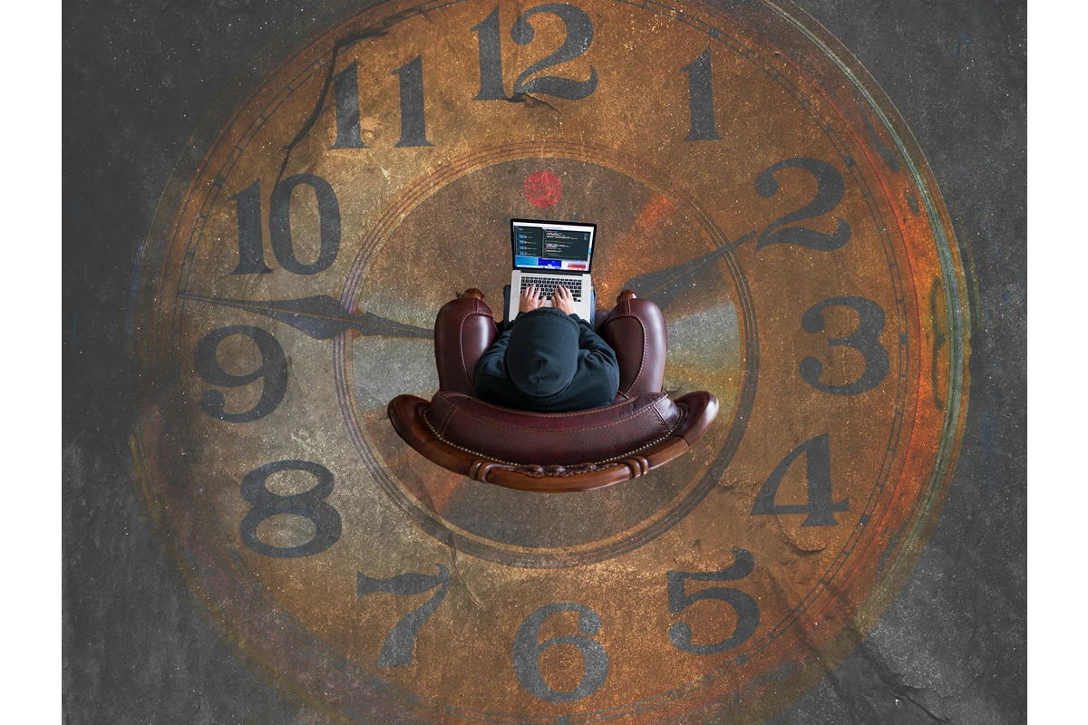 Overhead view of a person sitting on a chair on their computer with a design on the floor of a clock.