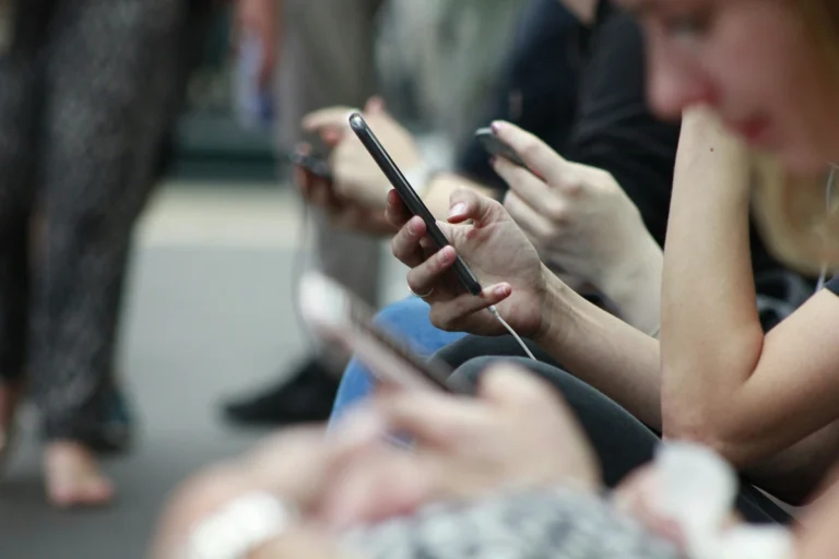Image of a few people looking down at their phones close up on hands