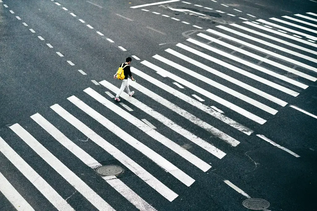 Image of person crossing the street wearing a yellow backpack