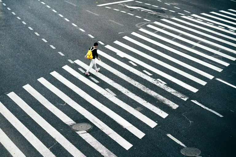 Image of person crossing the street wearing a yellow backpack