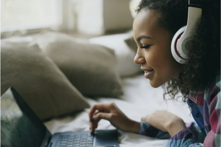 Image of teenager in bed on their laptop with headphones on