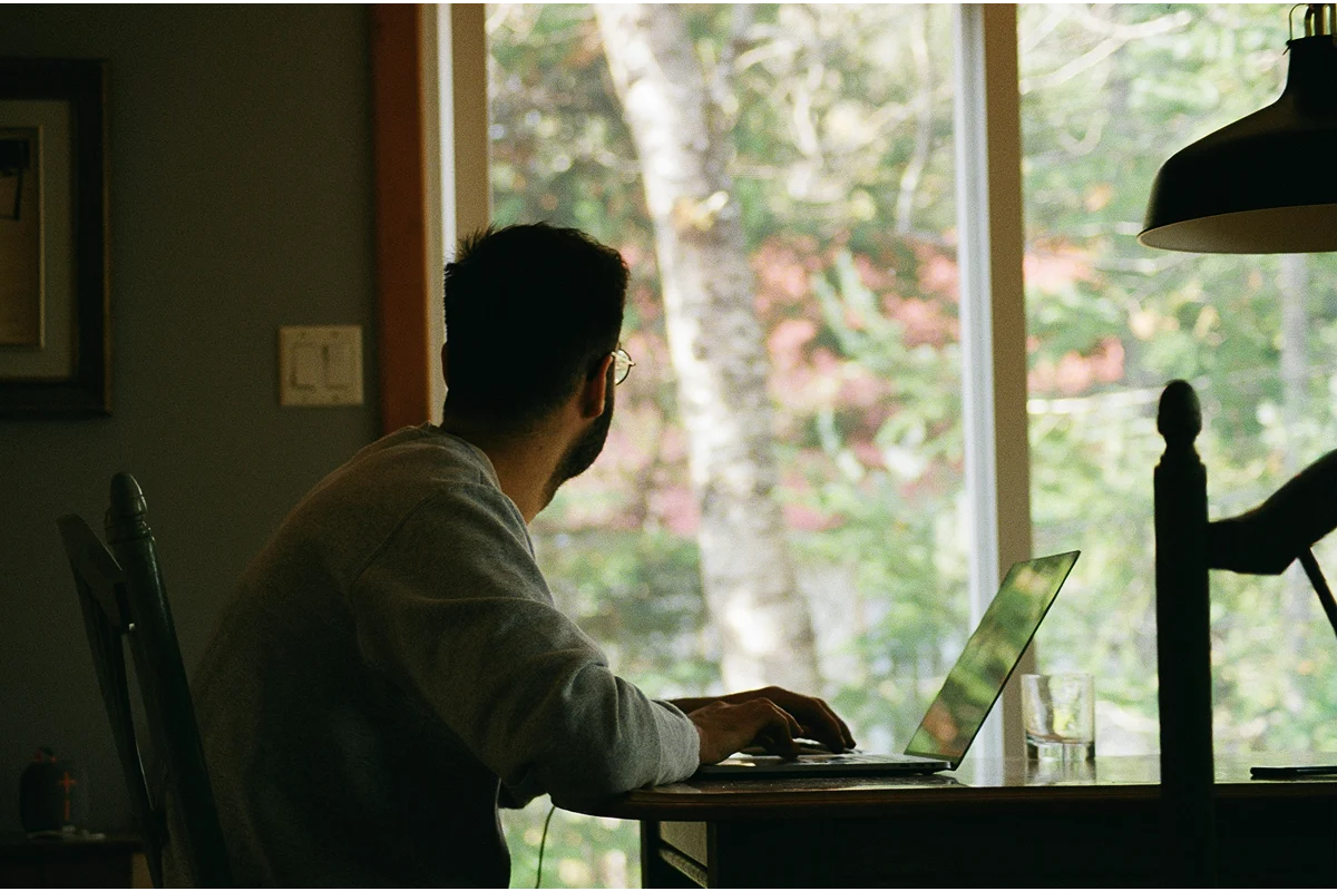 Image of a person working in front of a laptop looking out the window