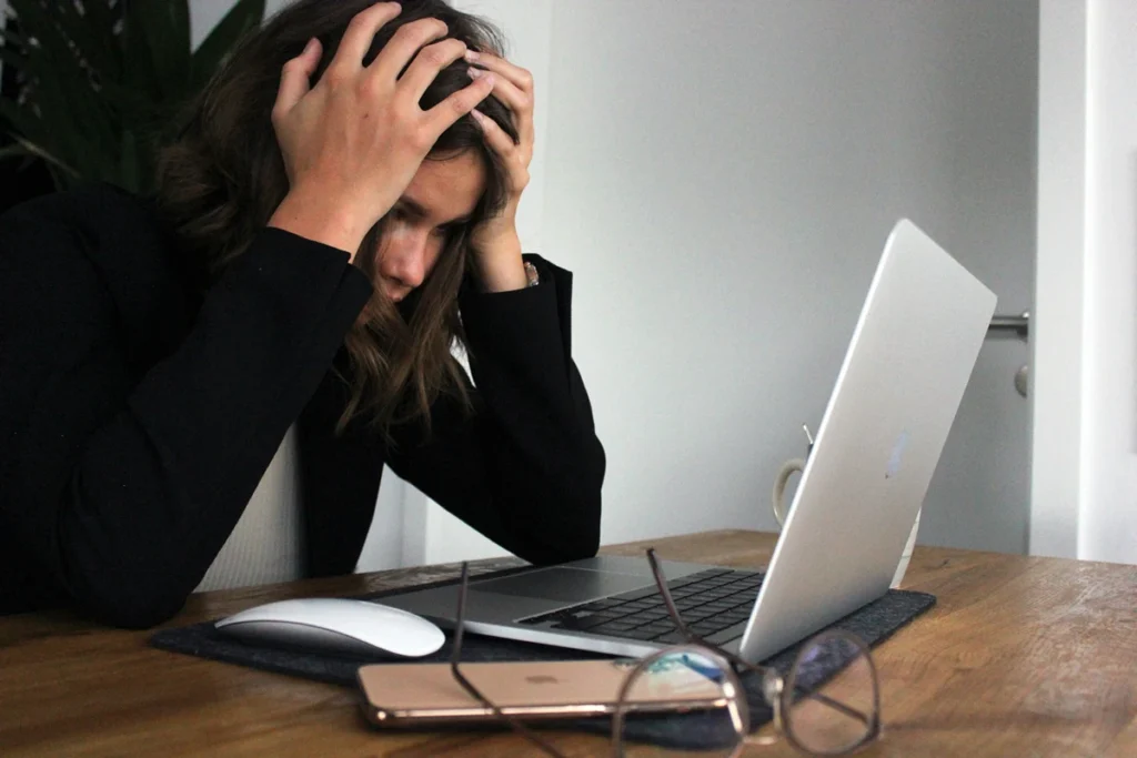 Woman in front of computer screen with head in hands
