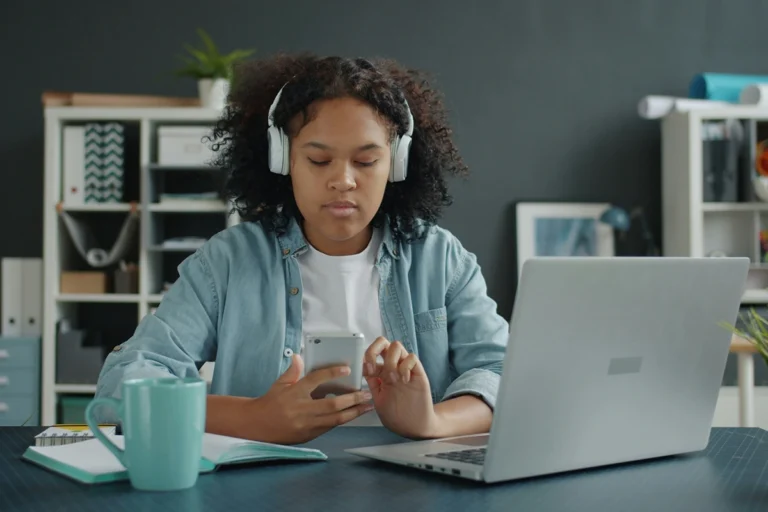 Image of person scrolling on phone at their desk