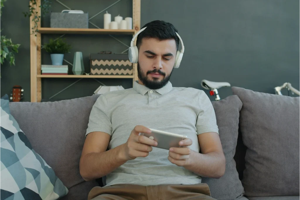 Image of person sitting on couch with headphones and phone