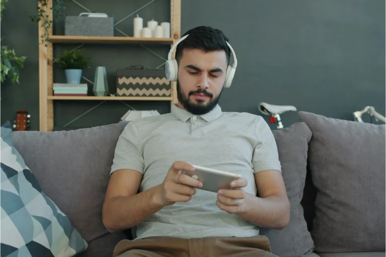 Image of person sitting on couch with headphones and phone
