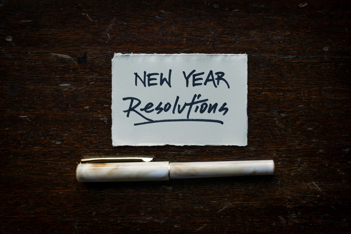 Paper and pen with "New Year Resolutions" written
