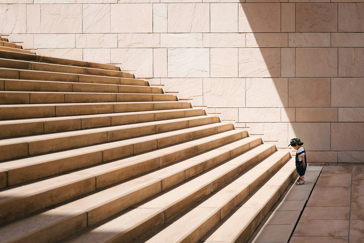Child at the bottom of stairs deciding if they are ready to make a change and go up