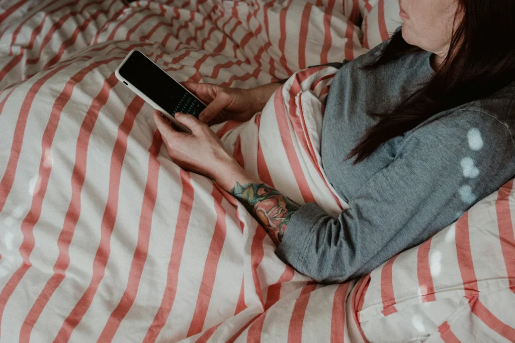 Person lying in bed while on their phone